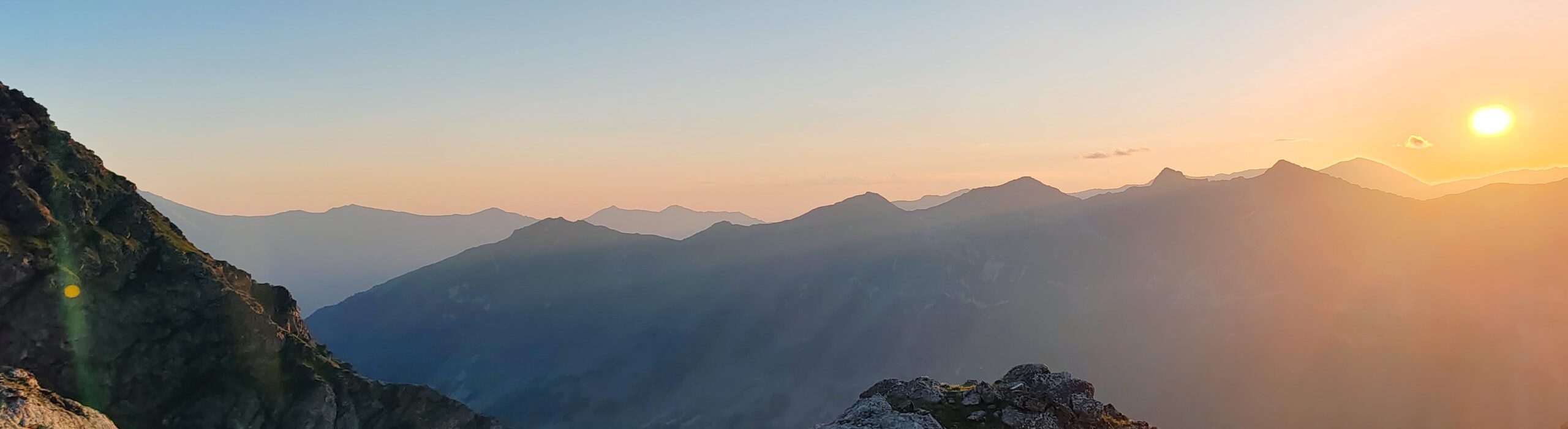 Stunning mountain view during sunset, showcasing vibrant colors, rocky terrain, and lush greenery, creating a serene atmosphere